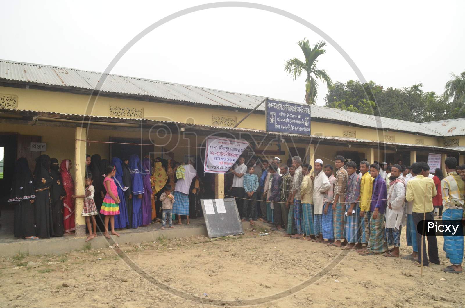 Indian Voters  Standing In Queue Lines For Casting Their Votes At Polling Booths During  Assam Assembly General Elections 2016