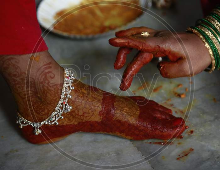 Indian Bride getting applying turmeric on her foot