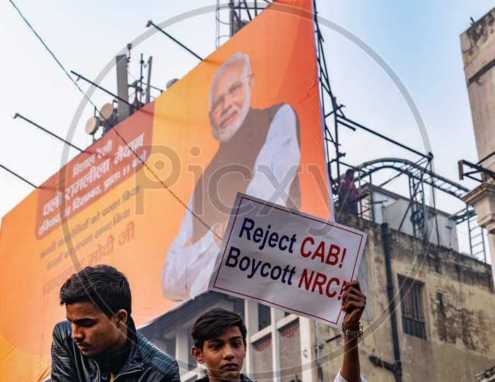 A man holding the banner and picture of PM Narendra Modi on a hoarding in background during Protest against CAA (Citizenship Amendment Act 2019) and NRC(National Register of Citizens)