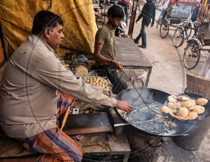 Varanasi, India December 15th, 2012: Near Dashashwamedh Ghat a vendor frying Puri (also spelled Poori) is an unleavened deep-fried bread and selling in the morning. A boy is helping him