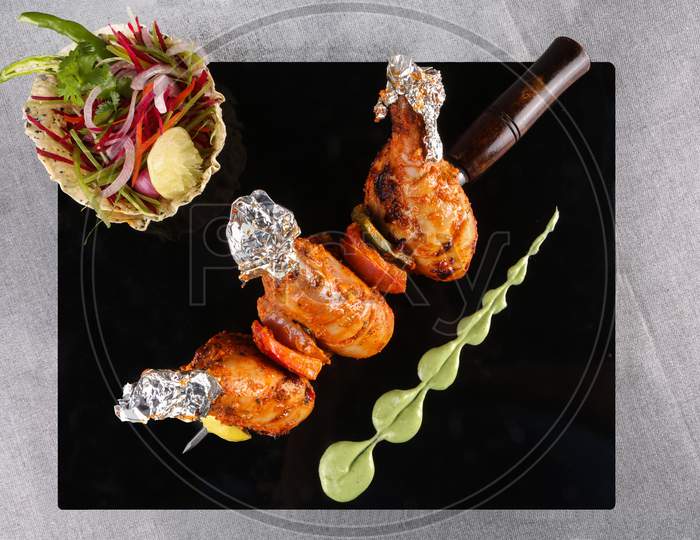 Delicious Stuffed Chicken Legs Roasted In Tandoor Served On A Black Platter With Salad