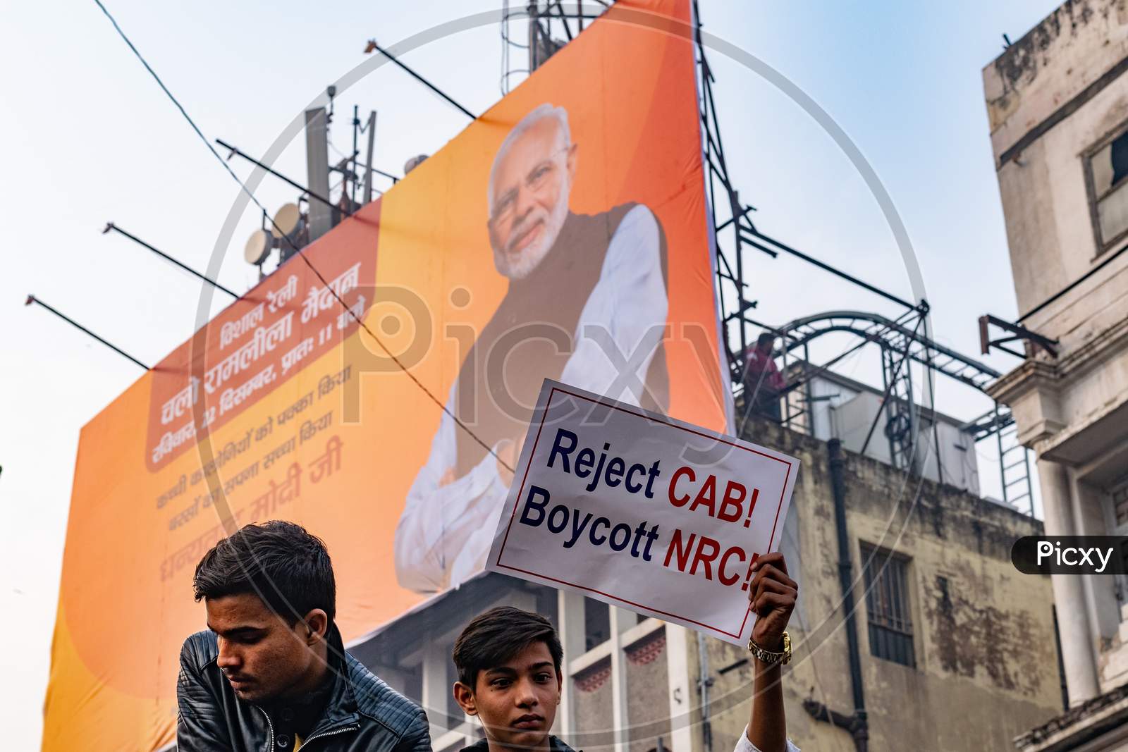 A man holding the banner and picture of PM Narendra Modi on a hoarding in background during Protest against CAA (Citizenship Amendment Act 2019) and NRC(National Register of Citizens)