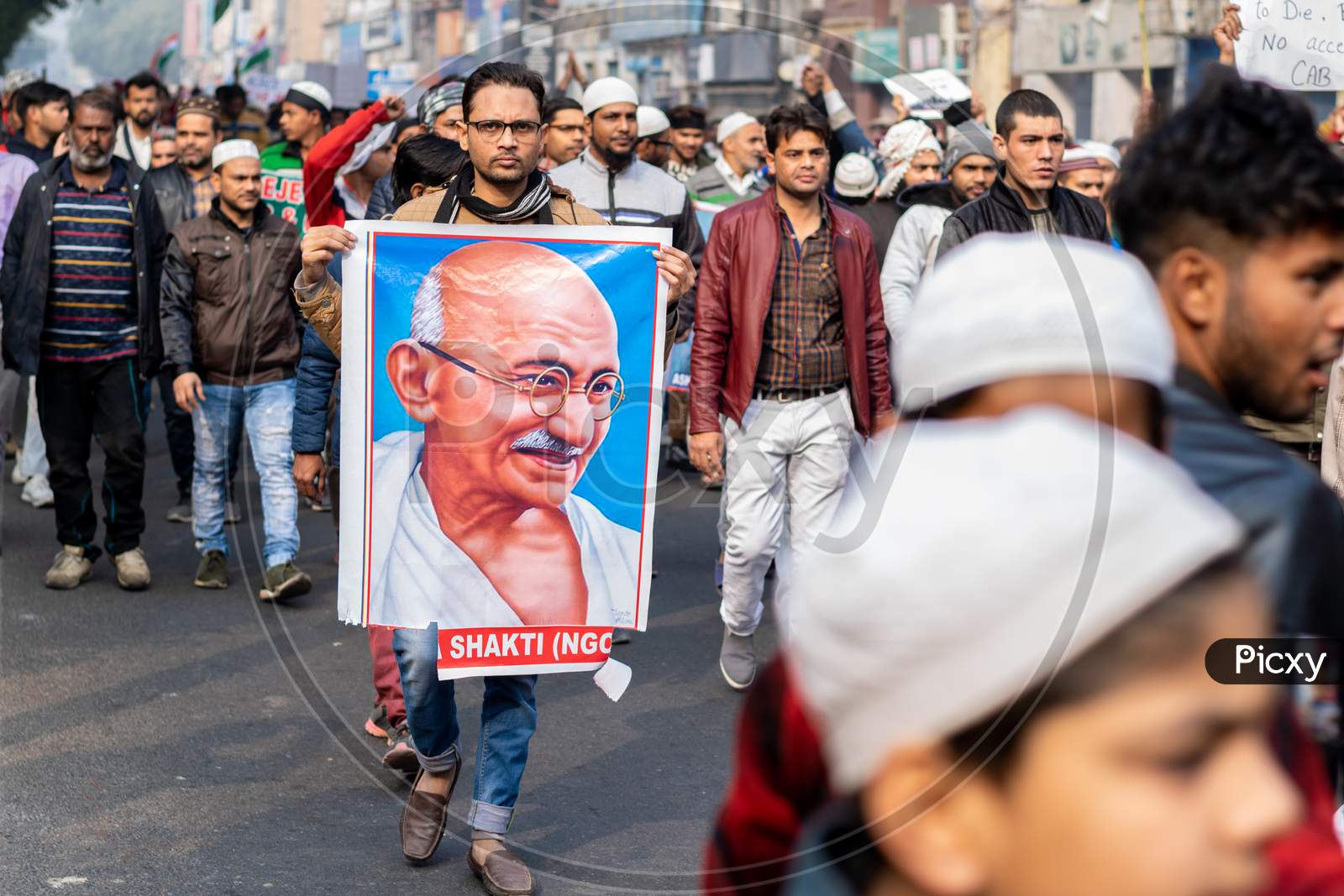 A man holding the picture of Mahatma Gandhi and others Protesting Against Caa And Nrc