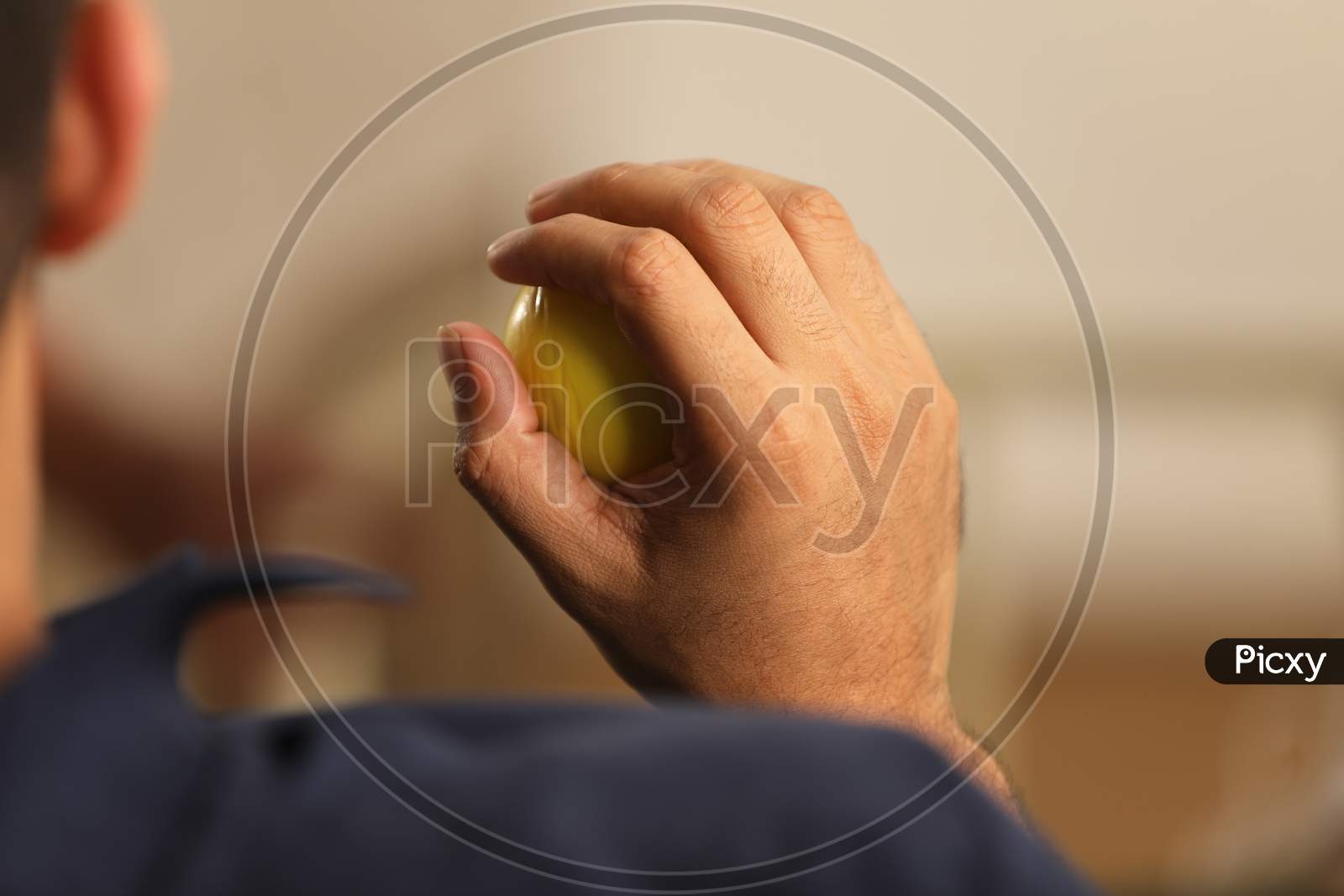 Man Pressing Stress Ball With Hand Closeup