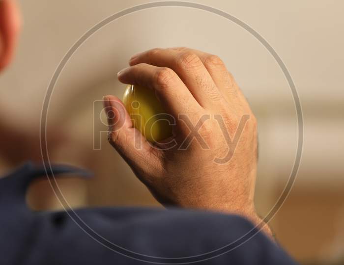 Man Pressing Stress Ball With Hand Closeup