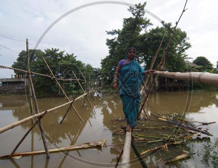 Food Affected Villagers Cross Flood Waters Through A Bamboo Bridge In The Flood Affected Morigaon District Of Assam State, India, On July 22,2016