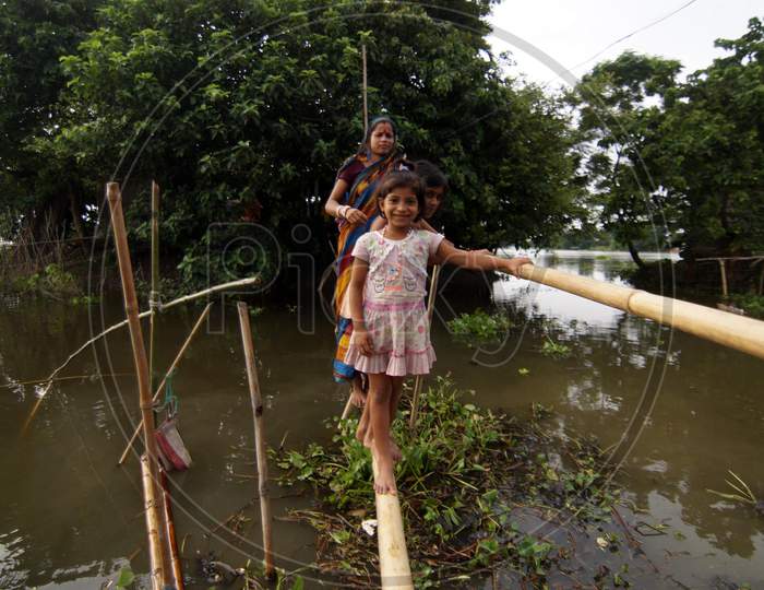 Food Affected Villagers Cross Flood Waters Through A Bamboo Bridge In The Flood Affected Morigaon District Of Assam State, India, On July 22,2016
