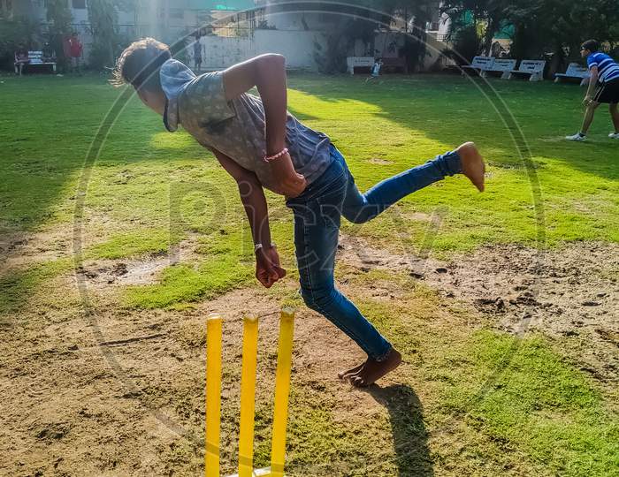 Young Indian Boys  Playing Cricket In A Lawn Garden