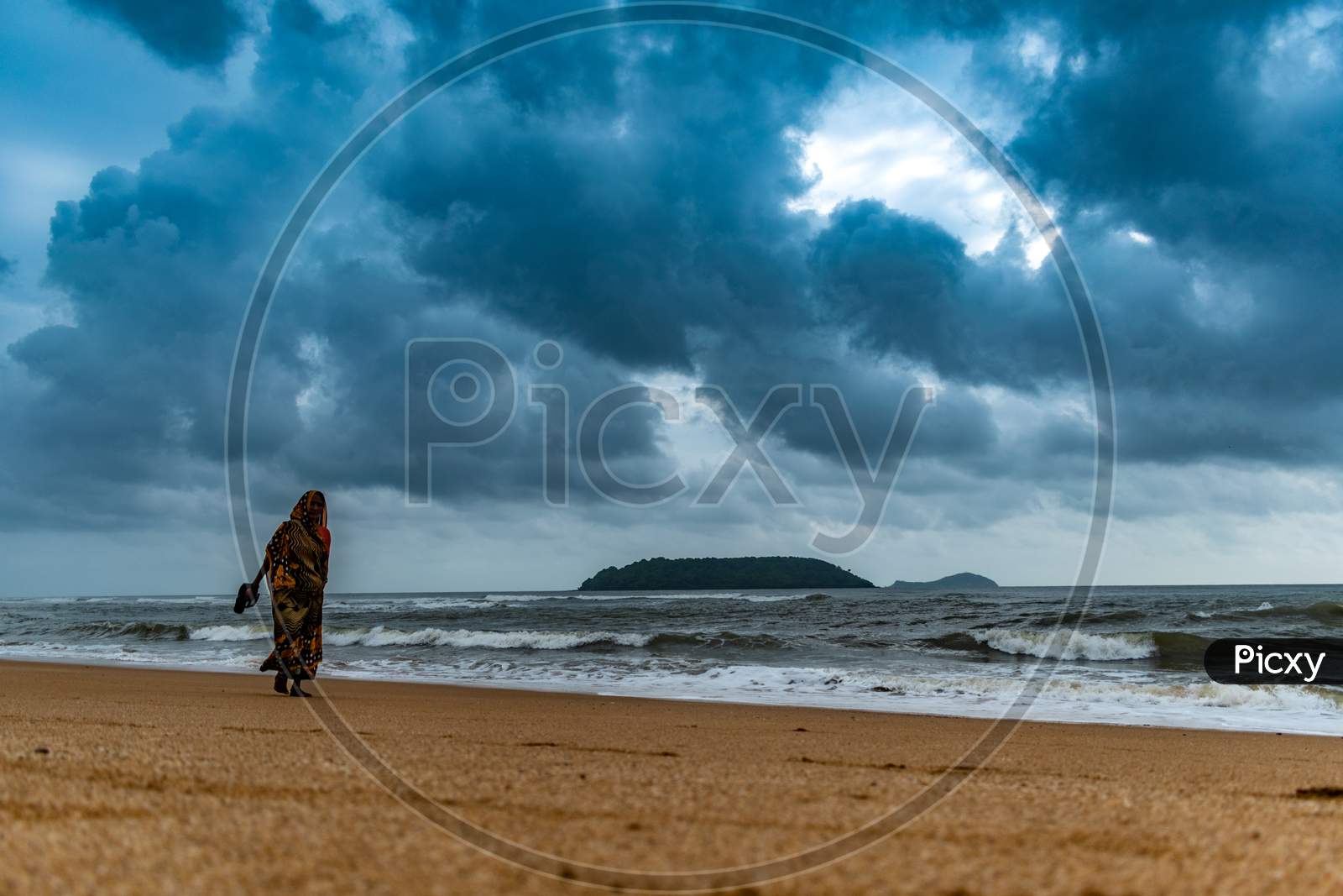 An Old Woman Walking In an Beach With Dark Clouds in Background