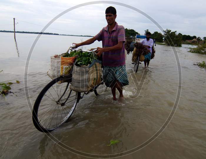 Villagers Crosses Flood Waters In The Flood Affected Morigaon District Of Assam On July 22,2016