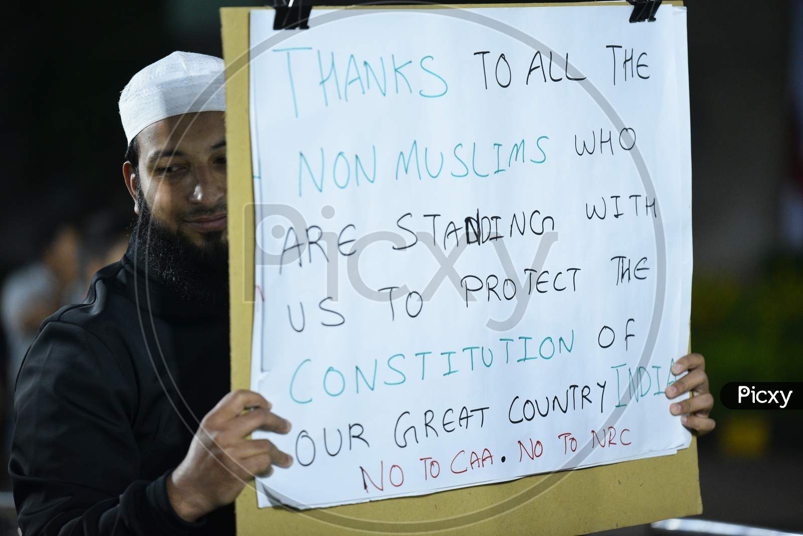 A muslim man holds placards at a protest against CAA and NRC at Osmania Arts College