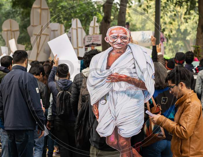 A student holding cutout of Mahatma Gandhi during Protest against Citizenship Amendment Act CAA and National Register of Citizens NRC
