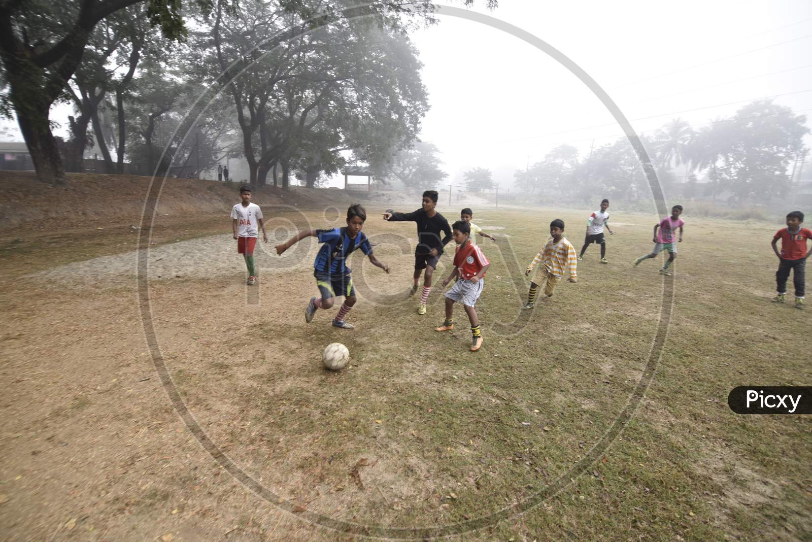 Children Playing Football  in A Ground on A Foggy Morning in Winter In  Guwahati, Assam
