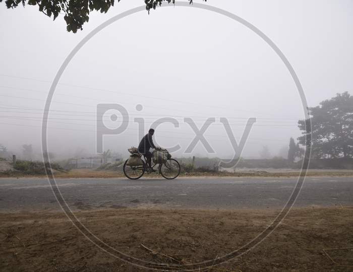 A Villager Riding A Bicycle on an Foggy Winter Morning in Guwahati