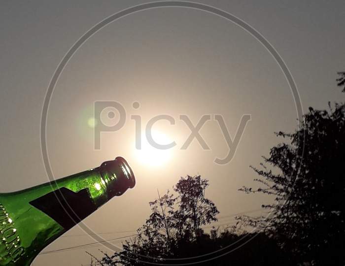 Beer Bottle With Bright Sun in Background