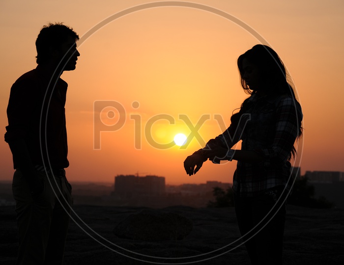 Silhouette Of Couple Over a Sunset Sky In Background