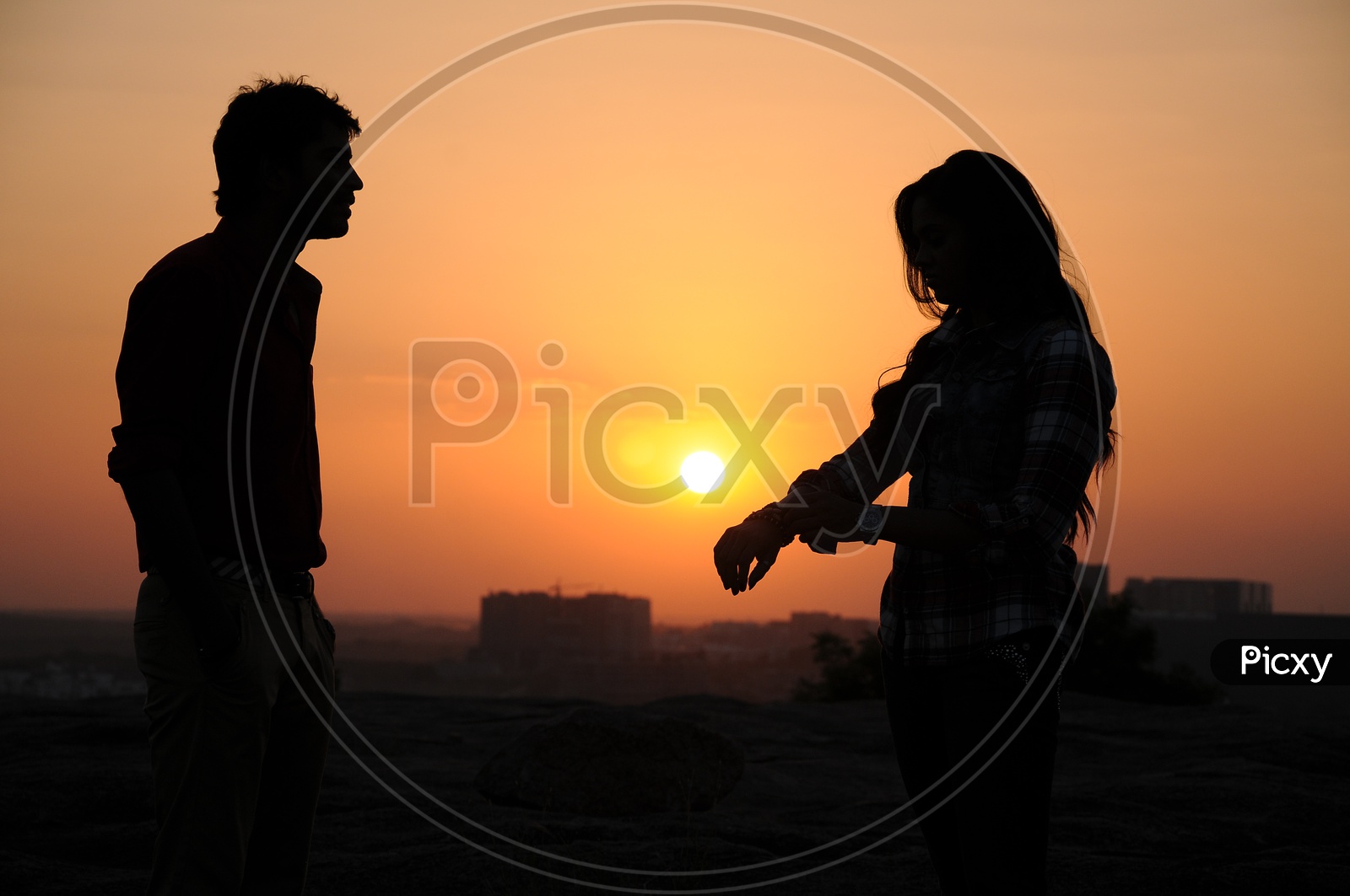Silhouette Of Couple Over a Sunset Sky In Background
