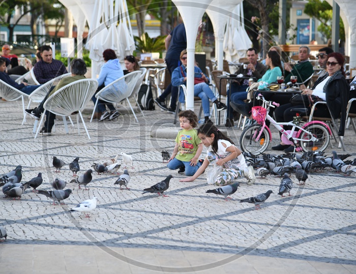 Children Playing With Pigeons At Town Square Lisbon