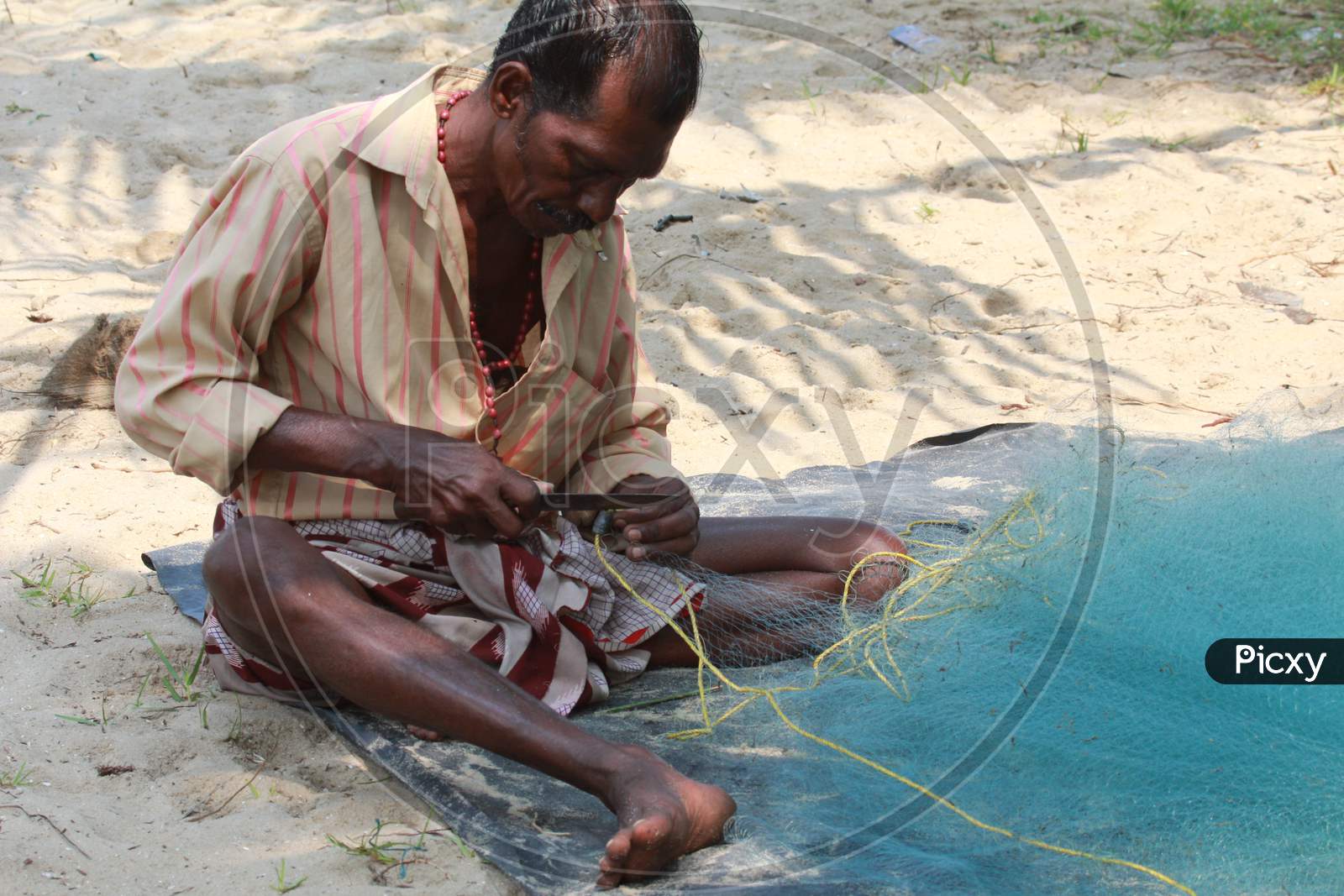 Fisherman stitching the Fishing Net
