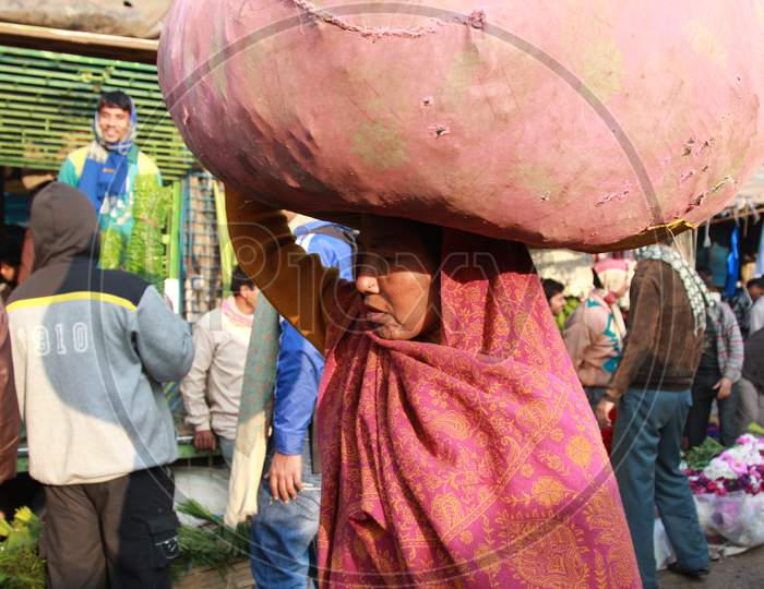 Indian Woman carrying a pile of clothes on her head