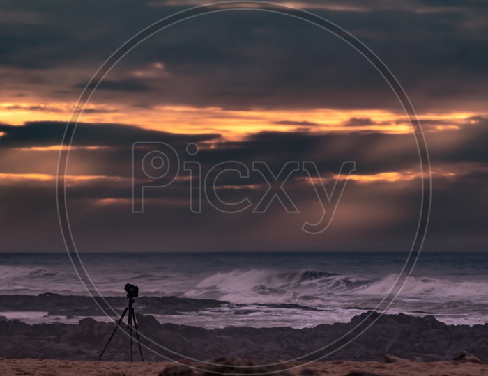 DSLR Mounted to Tripod At a Beach With Sunset Sky As Background
