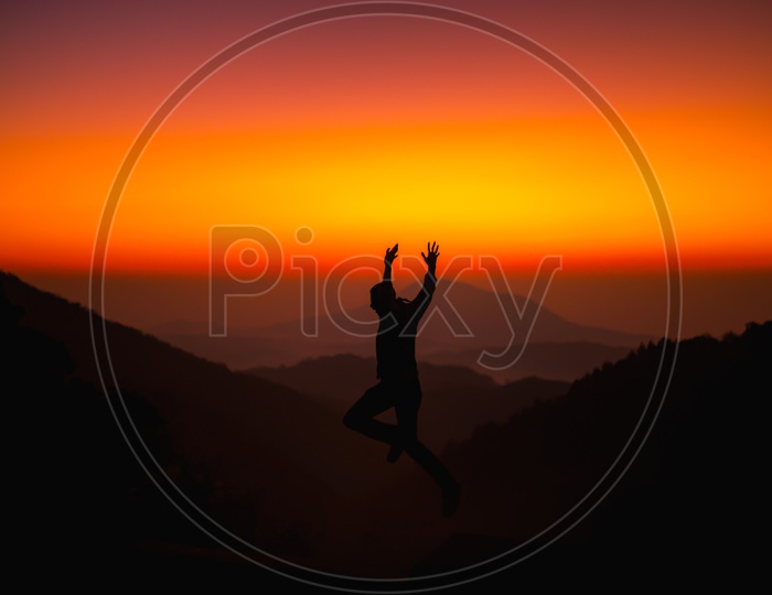 Silhouette Of Man Jumping In Joy Over Sunset Sky Background