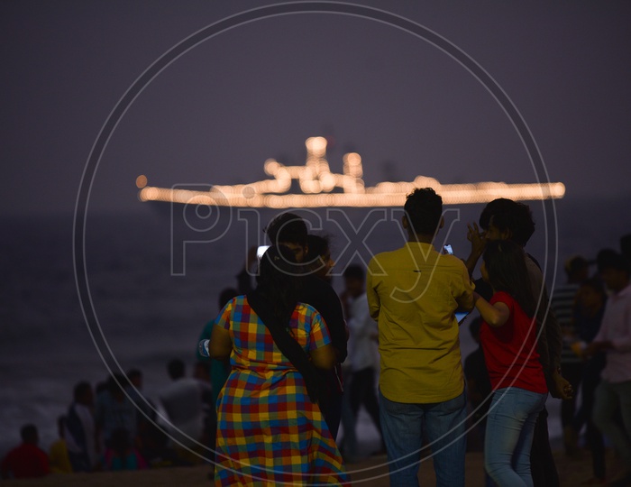 People watch a decorated Navy Ship on Navy Day,December 2019 in Visakhapatnam
