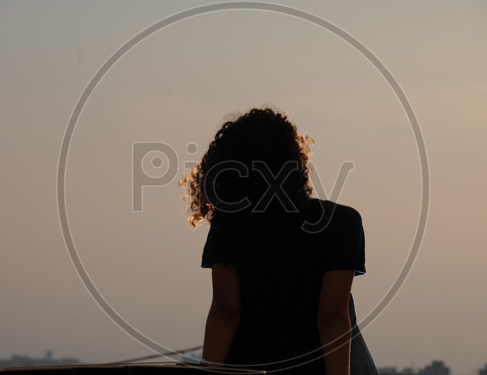 Silhouette of Woman Enjoying Sunset With A City