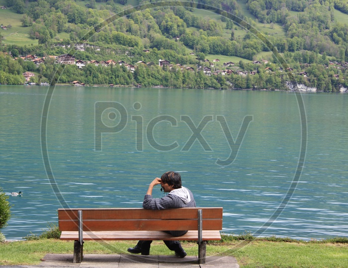 Man Sitting At a Bench With Lake Front in Background