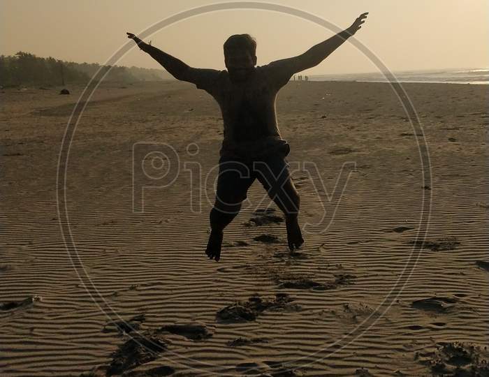 Man jumping in Perupalem Beach