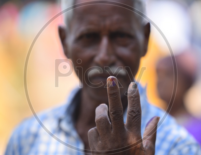 Indian old man showing his voted finger towards the camera