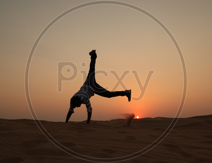 Silhouette of a man Jumping With Joy In Desert with a sunset In Background