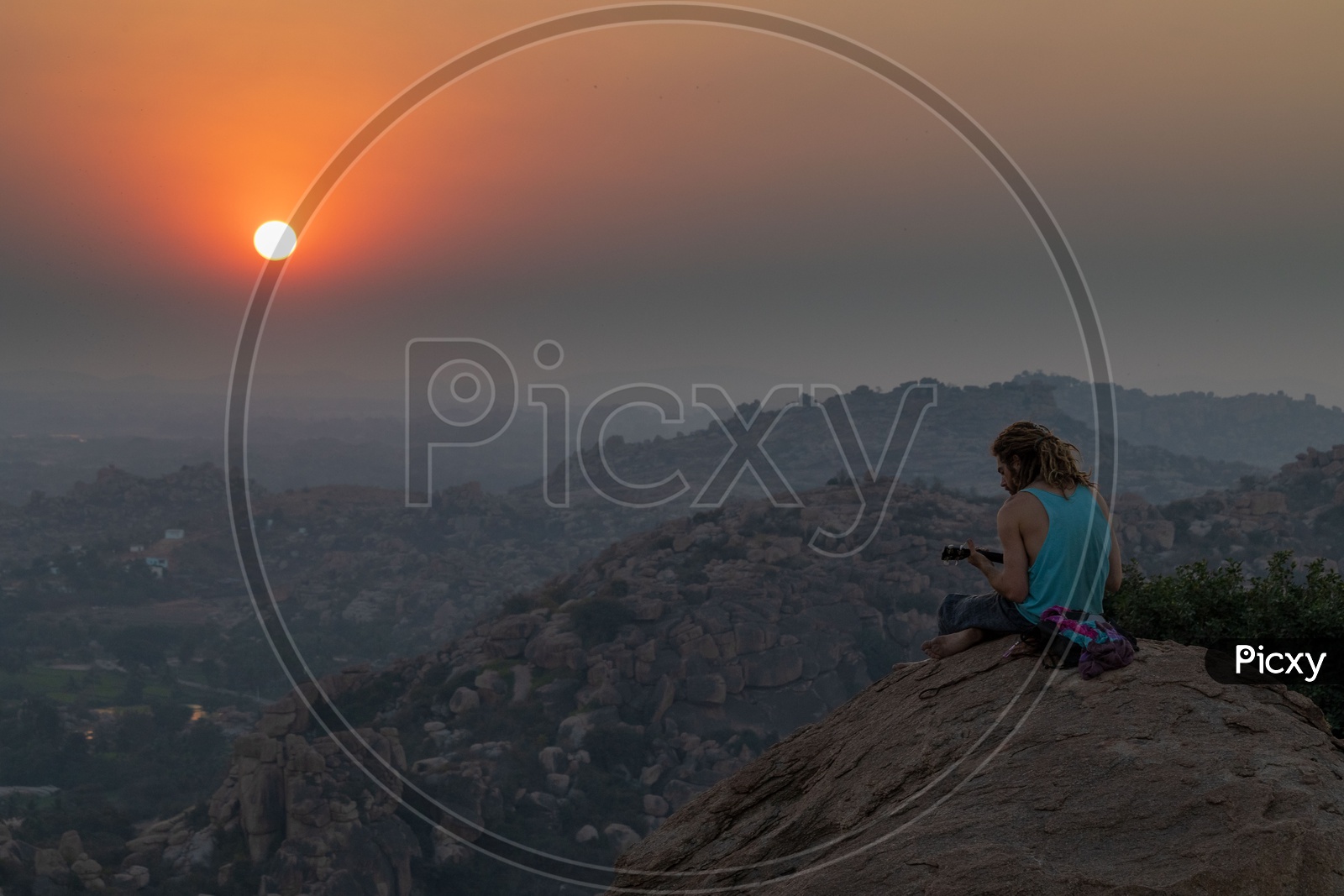 A man playing music on the hills of Hampi during Sunset