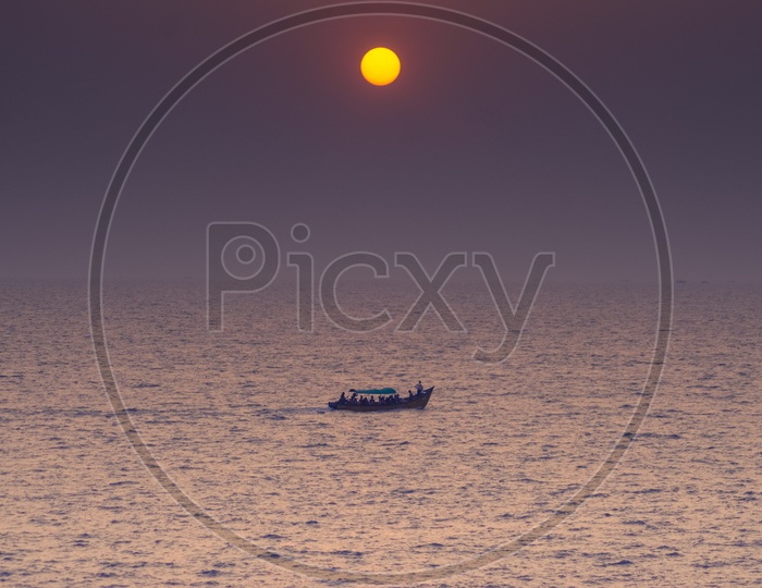 Photograph of boat sailing in Goa with Beautiful sun in the Background