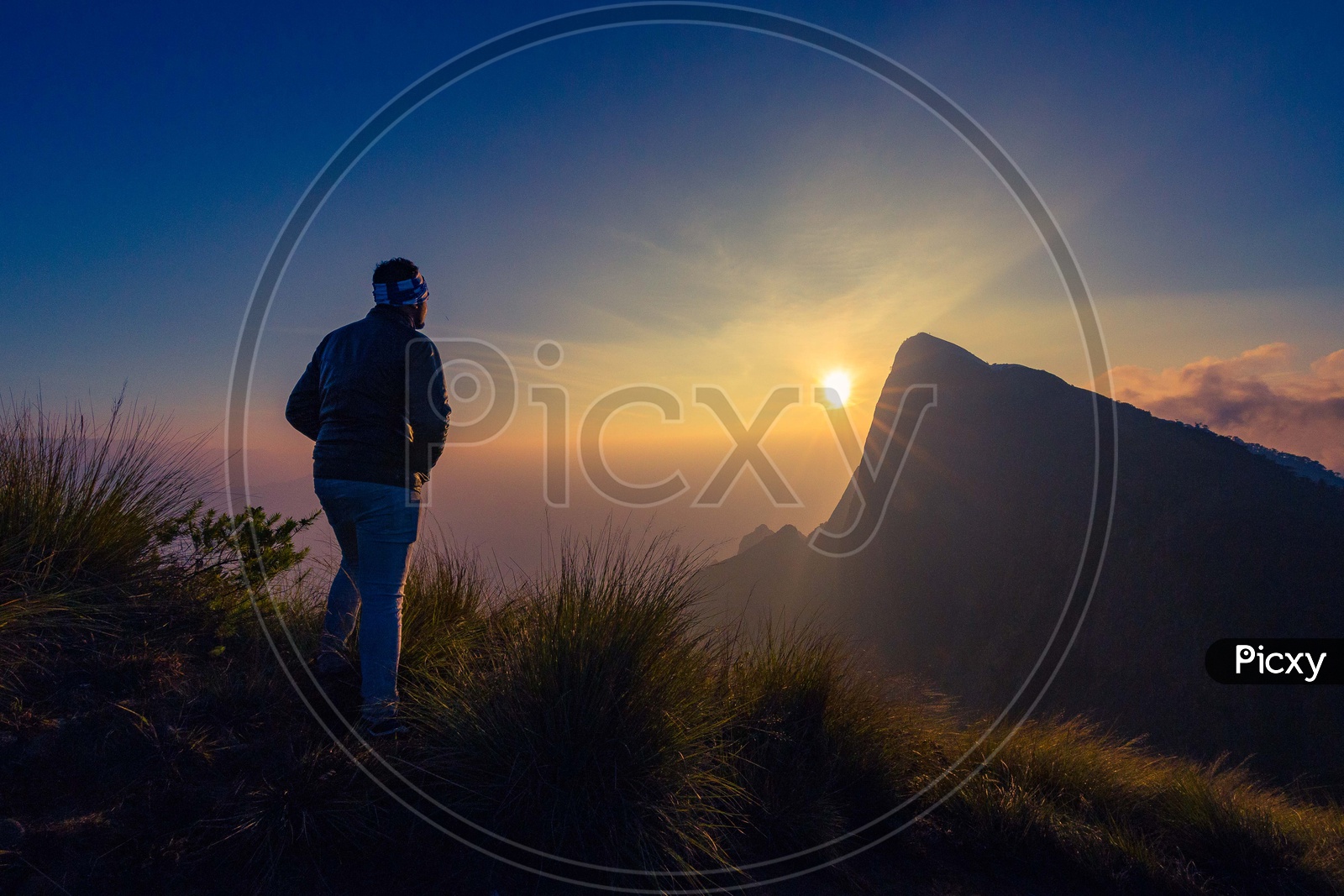 A man standing in a silhouette on the mountain during the sunrise