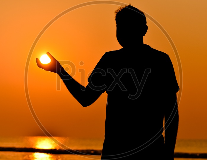 Silhouette of a man as if holding the Sun