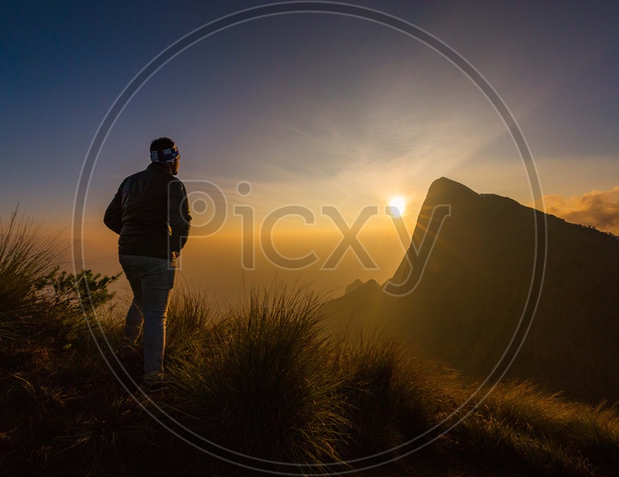 A man standing in a silhouette on the mountain during the sunrise