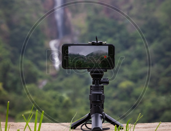 Mobile Phone Mounted On a Tripod Over a Water fall Location