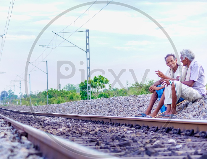 Two old men sitting besides the railway tracks