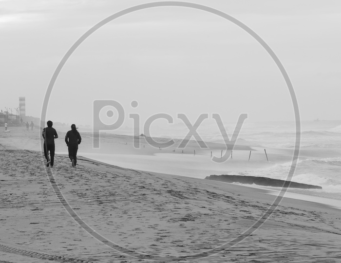 Silhouette of man and woman jogging alongside the beach