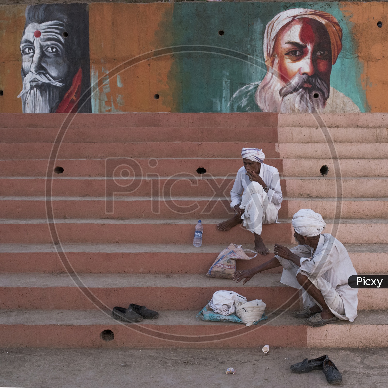 Old men sat on Steps and Paintings on wall in Background
