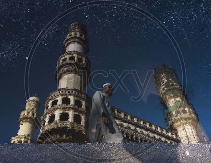 Reflections of Charminar and an old Muslim Man walking
