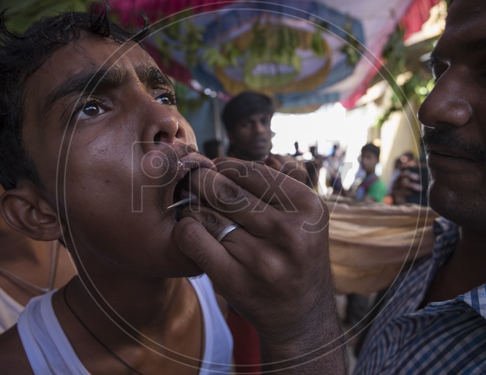 A boy having needle in his mouth for Festival of Kali Kaveripattinam