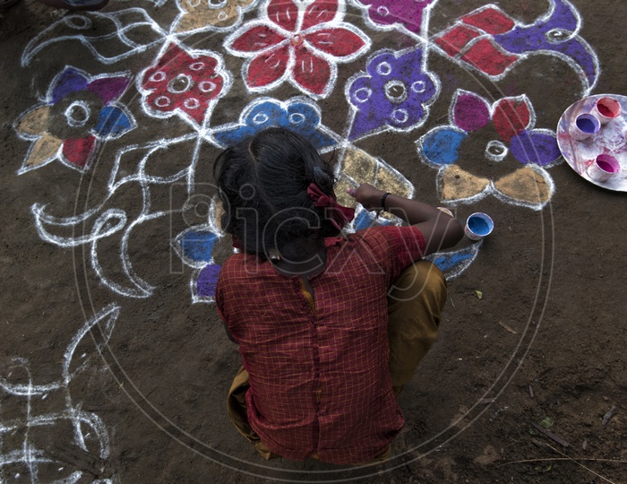 Indian girl making a rangoli outside her home