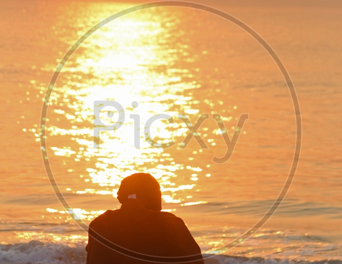 A person sitting alone at RK beach during the sunrise