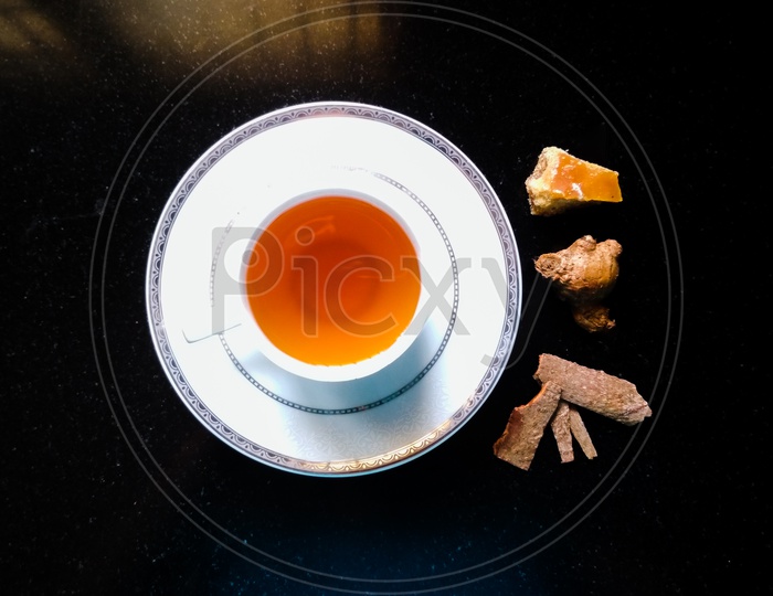 White ceramic tea cup with black tea - ginger, jagree, cassia bark