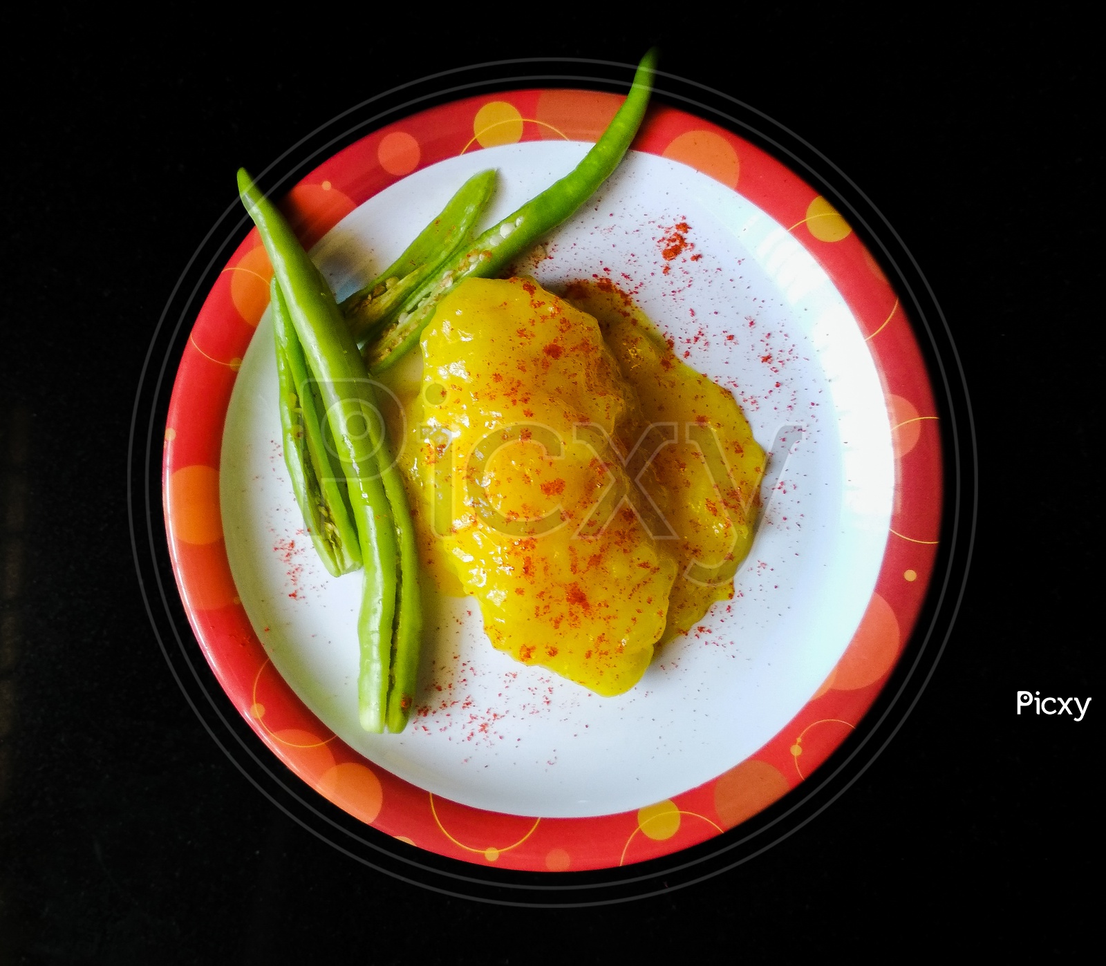 A plate with boiled mango dal and green chillies