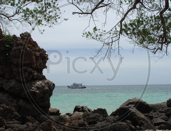 A boat seen at a distance in a beach through the rocks