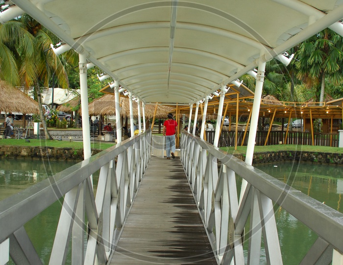 Man walking on Boardwalk of the bridge alongside a resort