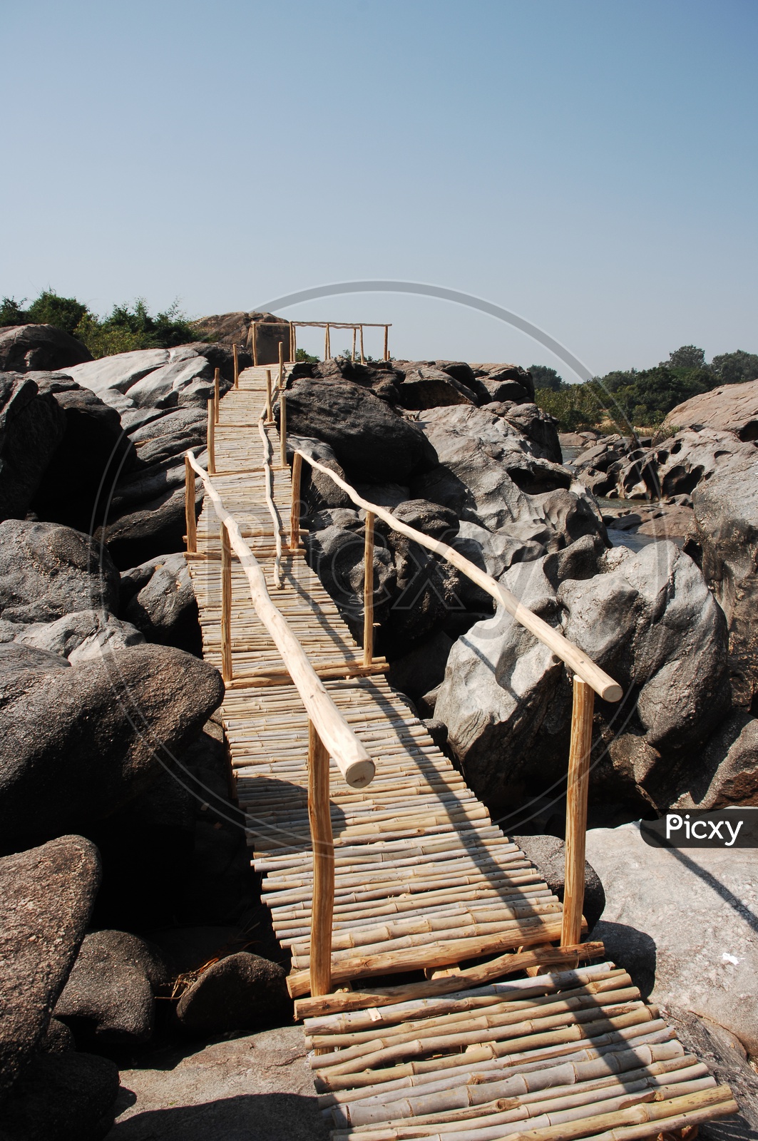 Log footbridge on the rocks over the river